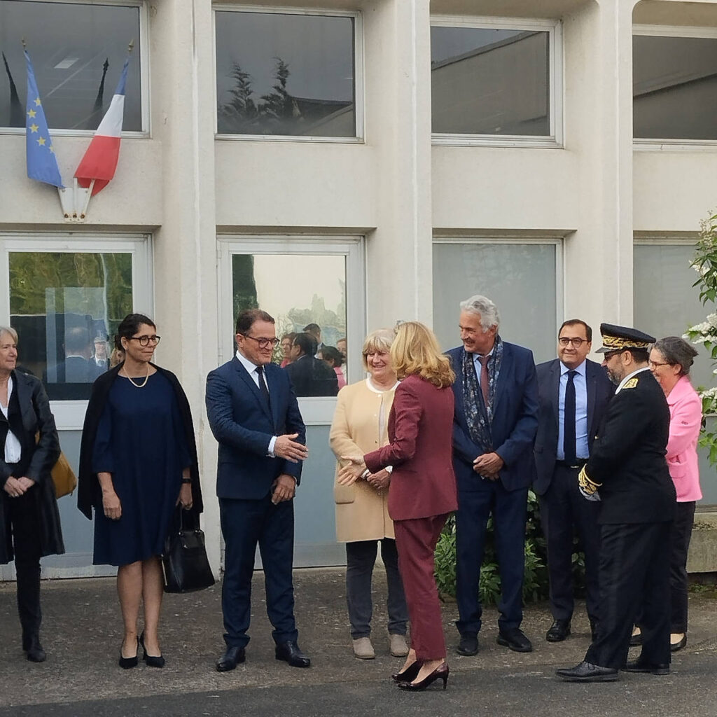 Une ministre serre la main d'un conseiller municipal devant une école.