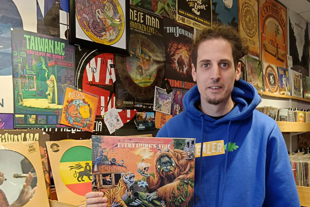 Portrait du disquaire tenant une pochette de disque vinyle.