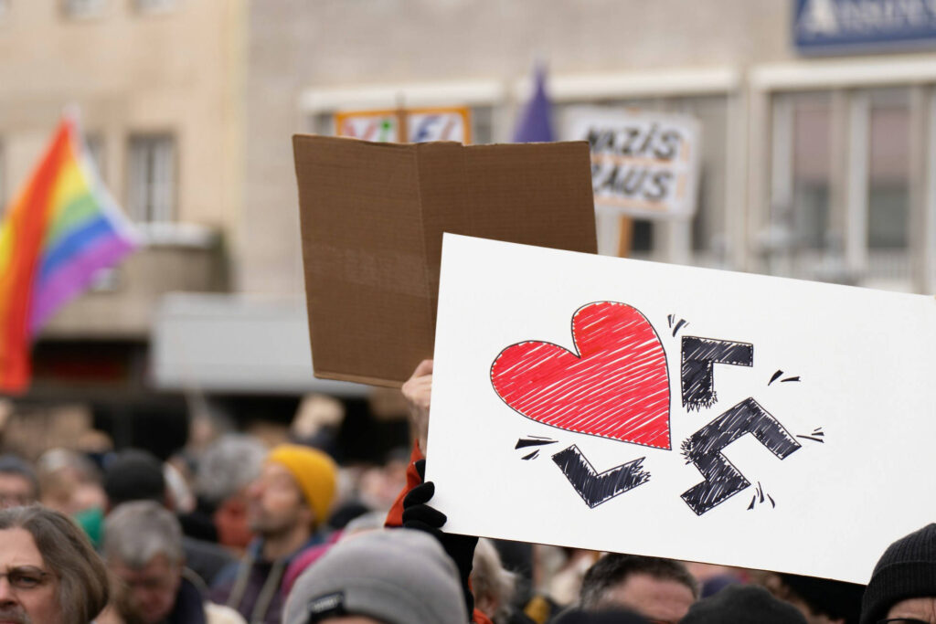Manifestation antinazie, un homme tient une pancarte sur laquelle un cœur détruit une croix gammée.
