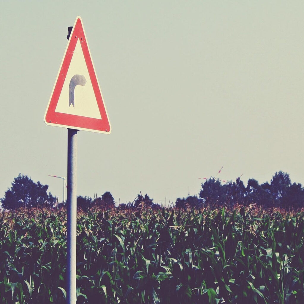 Un panneau indicateur planté dans la campagne signale un virage à droite.