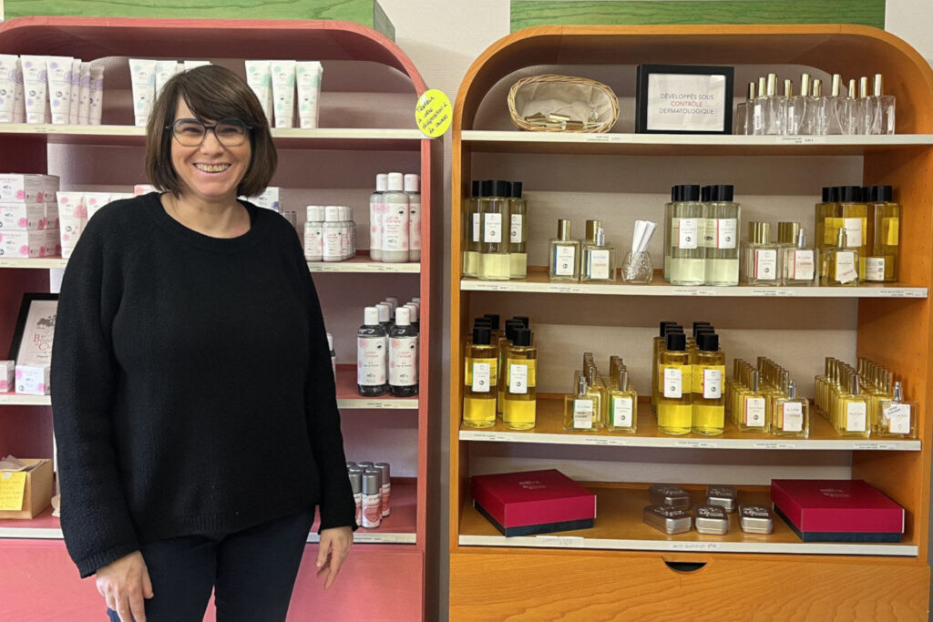Sonia se tient devant une sélection de produits vendus au sein de la boutique de l'abbaye.