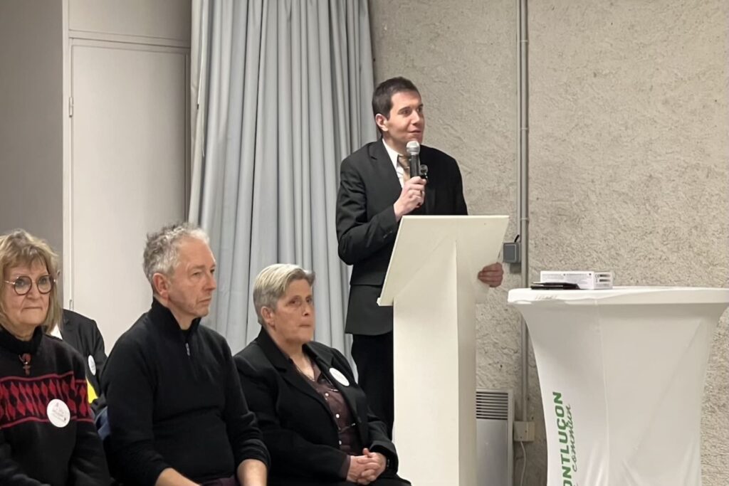 Debout, Pierre Mothet prend la parole derrière un pupitre en compagnie de plusieurs personnes (assises) de sa liste.