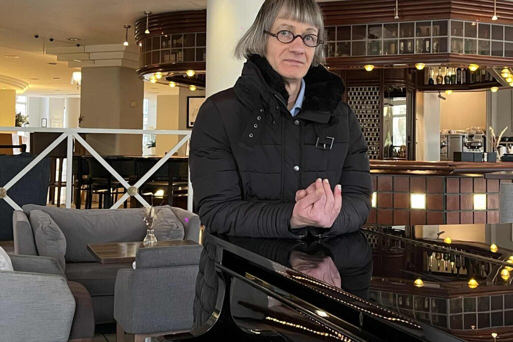 Avec sa coupe au carré et ses petites lunettes rondes, Saint-Philippe pose sur un piano à l’hôtel Vichy Célestins.
