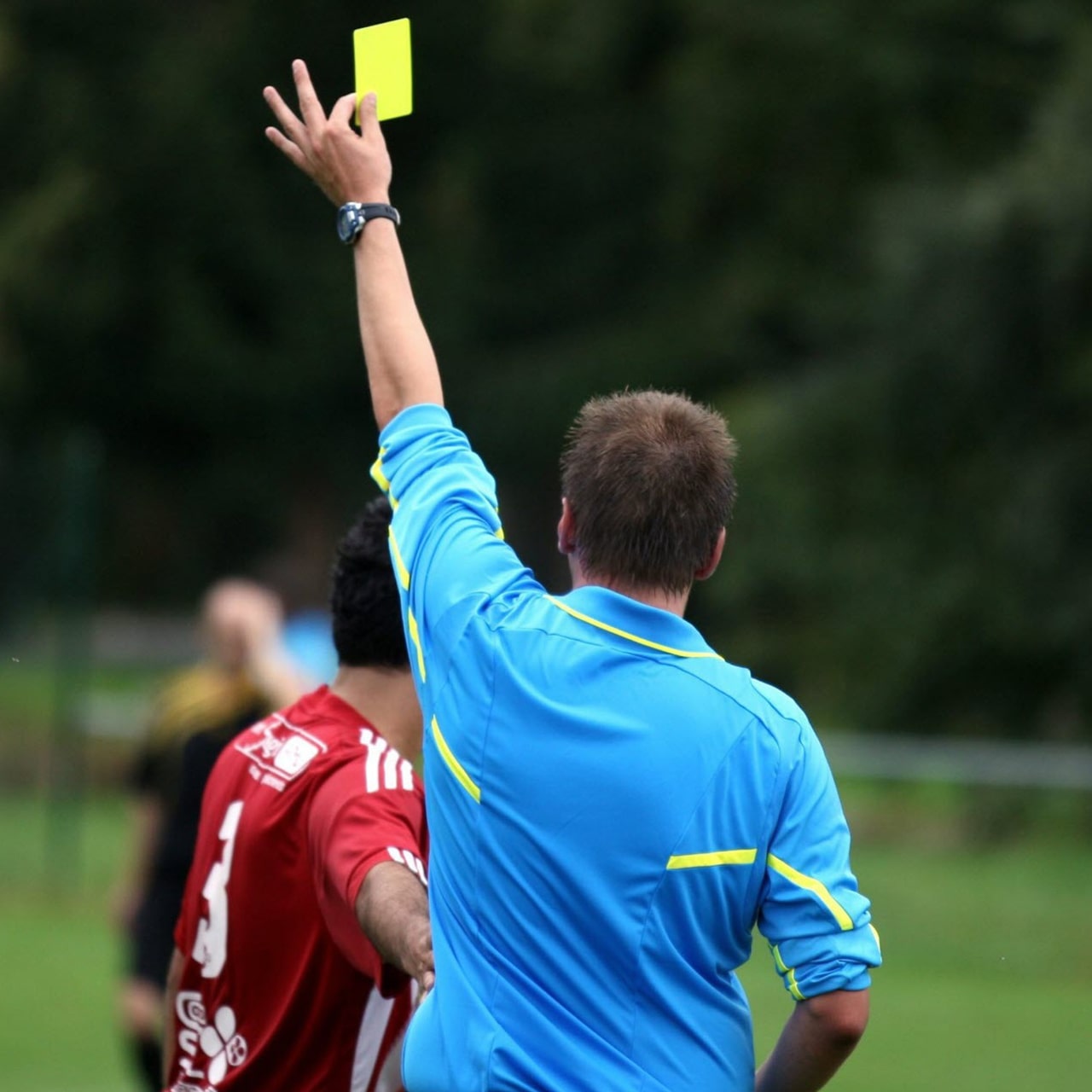 Un arbitre distribue un carton à un joueur ayant effectué une faute.
