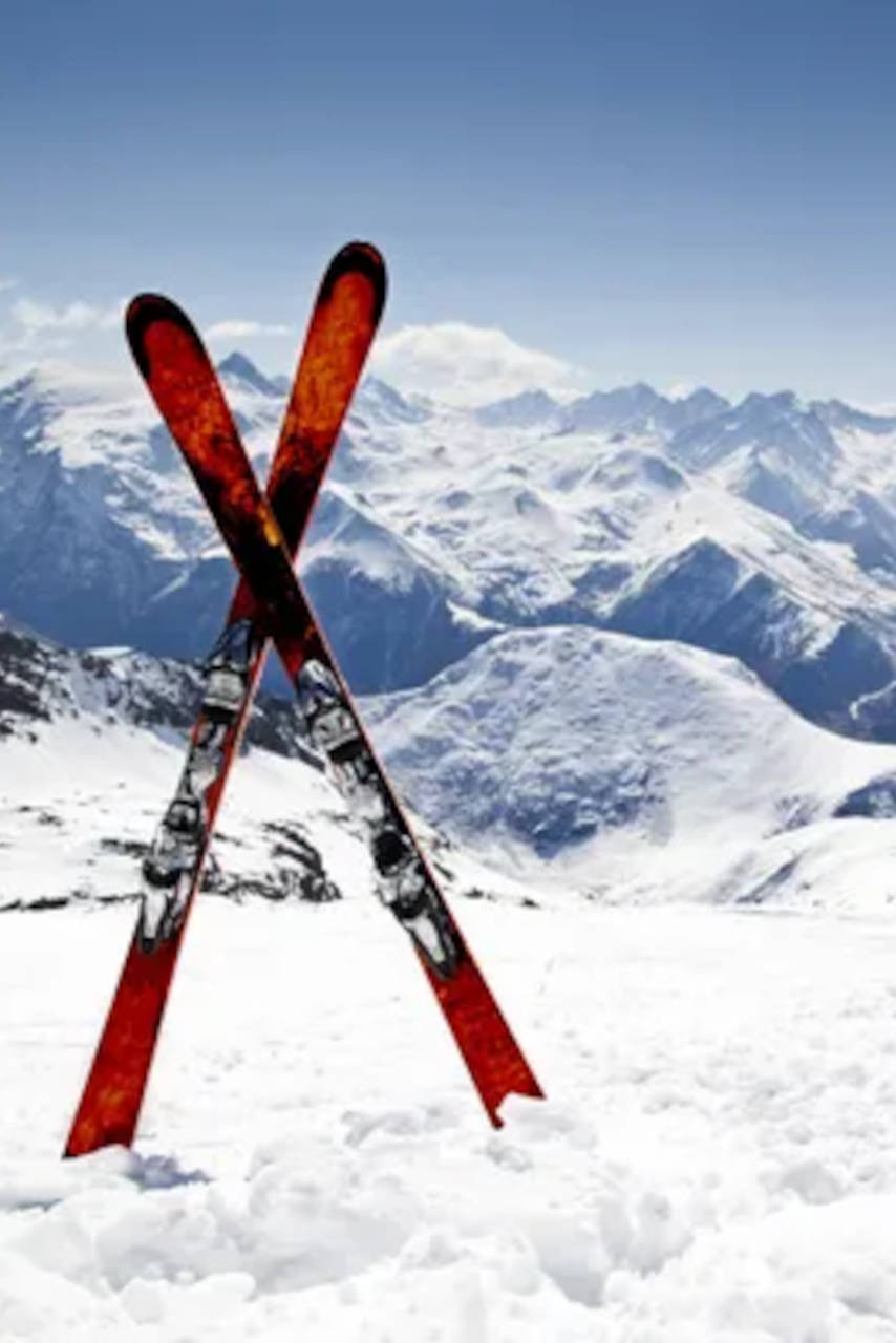 Des skis croisés devant un paysage de montagnes enneigées.