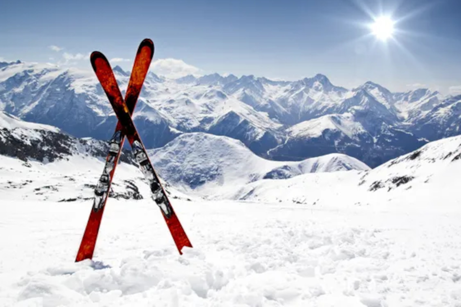 Des skis croisés devant un paysage de montagnes enneigées.