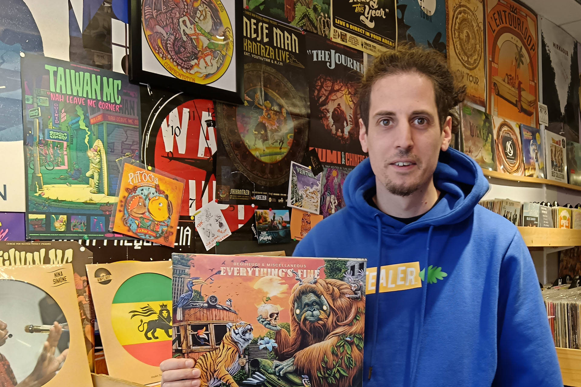 Portrait du disquaire tenant une pochette de disque vinyle.