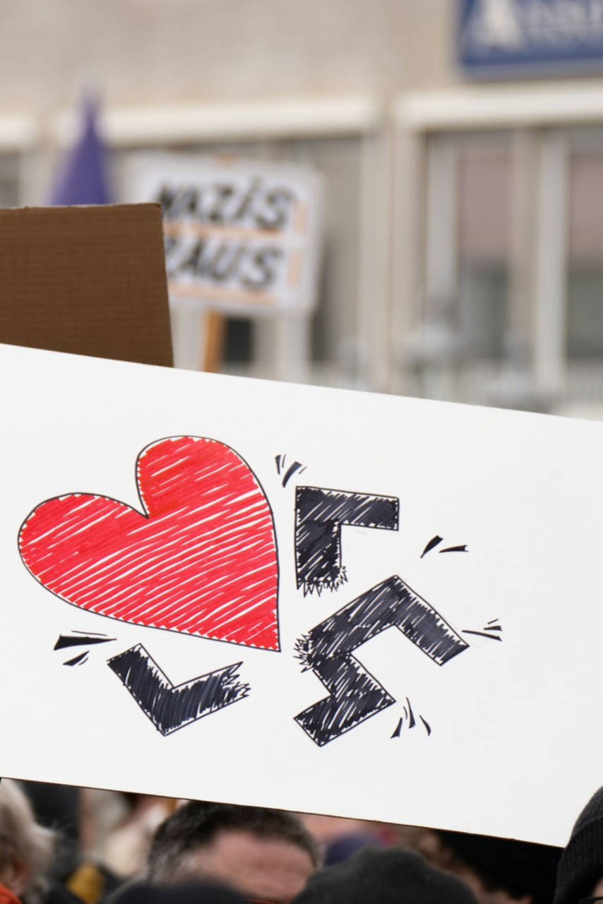 Manifestation antinazie, un homme tient une pancarte sur laquelle un cœur détruit une croix gammée.