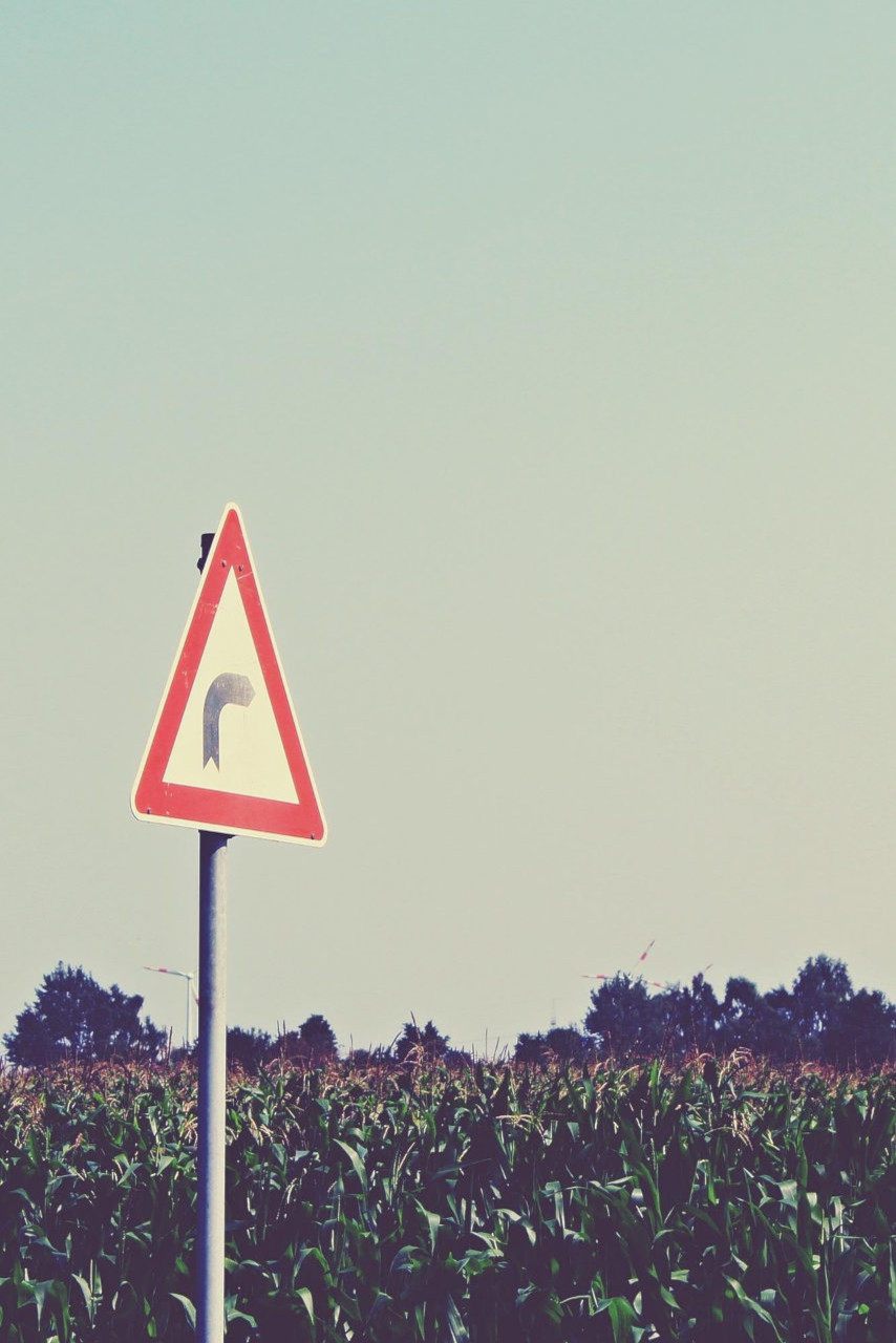 Un panneau indicateur planté dans la campagne signale un virage à droite.