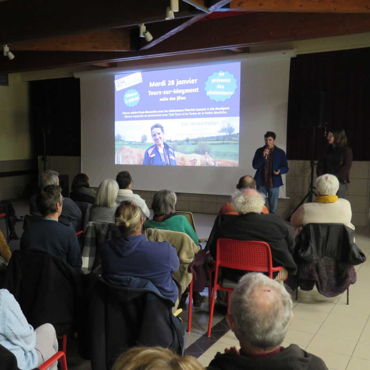 Une projection de cinéma, présentée par un intervenant au micro.