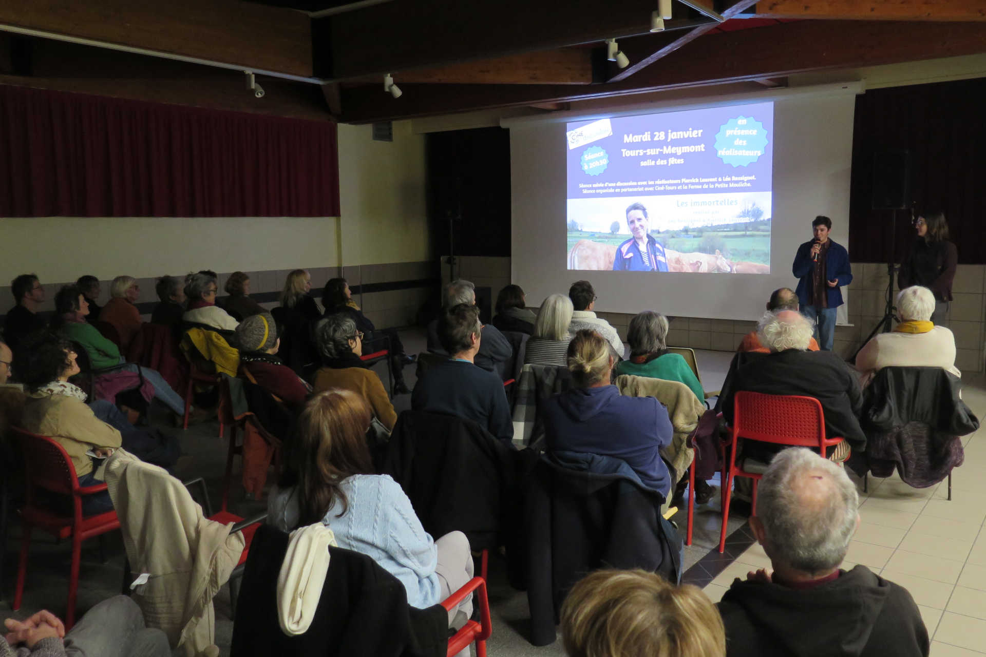 Une projection de cinéma, présentée par un intervenant au micro.