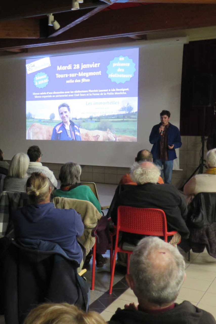 Une projection de cinéma, présentée par un intervenant au micro.