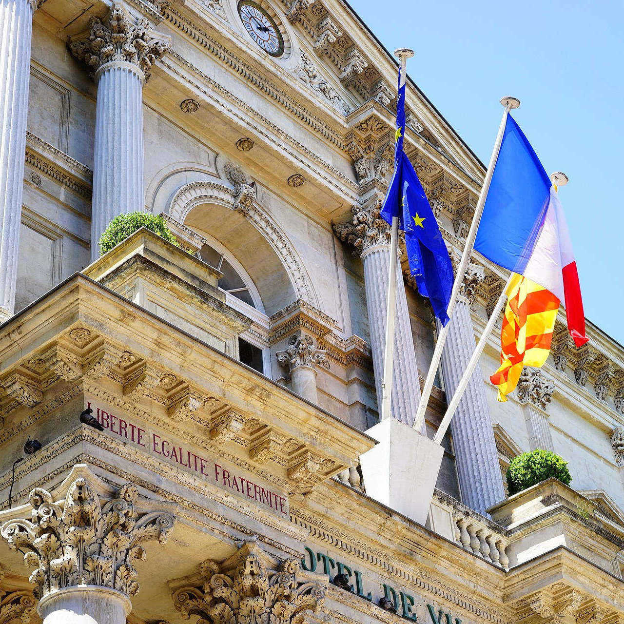 Fronton d'un hôtel de ville avec drapeaux français et européen.