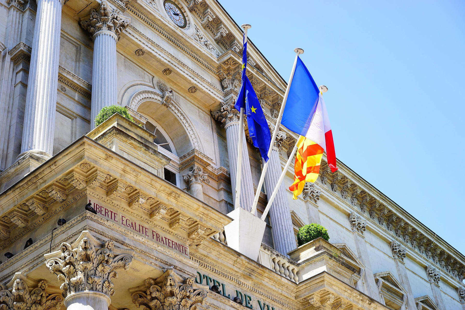 Fronton d'un hôtel de ville avec drapeaux français et européen.