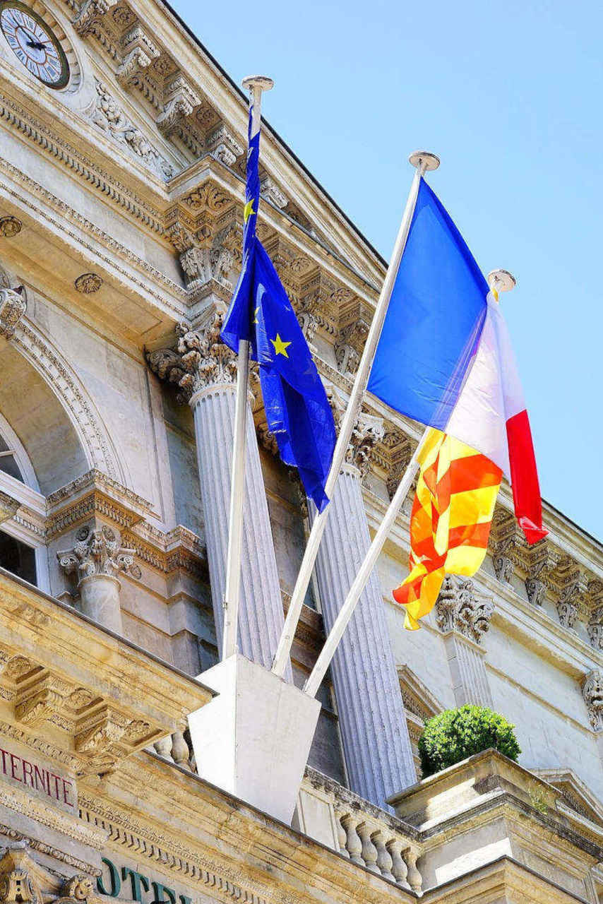 Fronton d'un hôtel de ville avec drapeaux français et européen.
