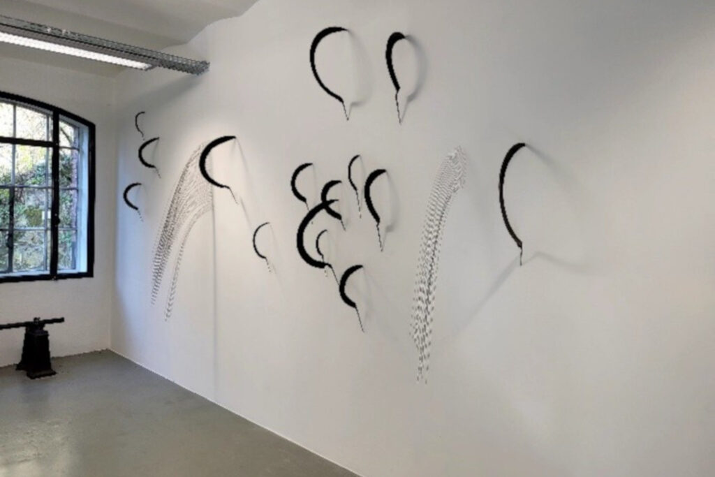 Exposition Creux de l'enfer : des faucilles et cordes de piano sur mur blanc.