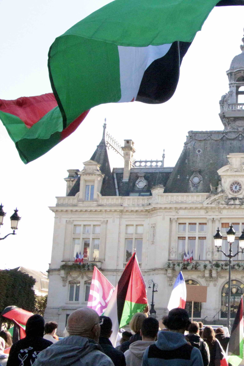 Des drapeaux palestiniens et des pancartes de soutien à la Palestine flottent au-dessus du cortège de manifestants qui se dirige vers la mairie.