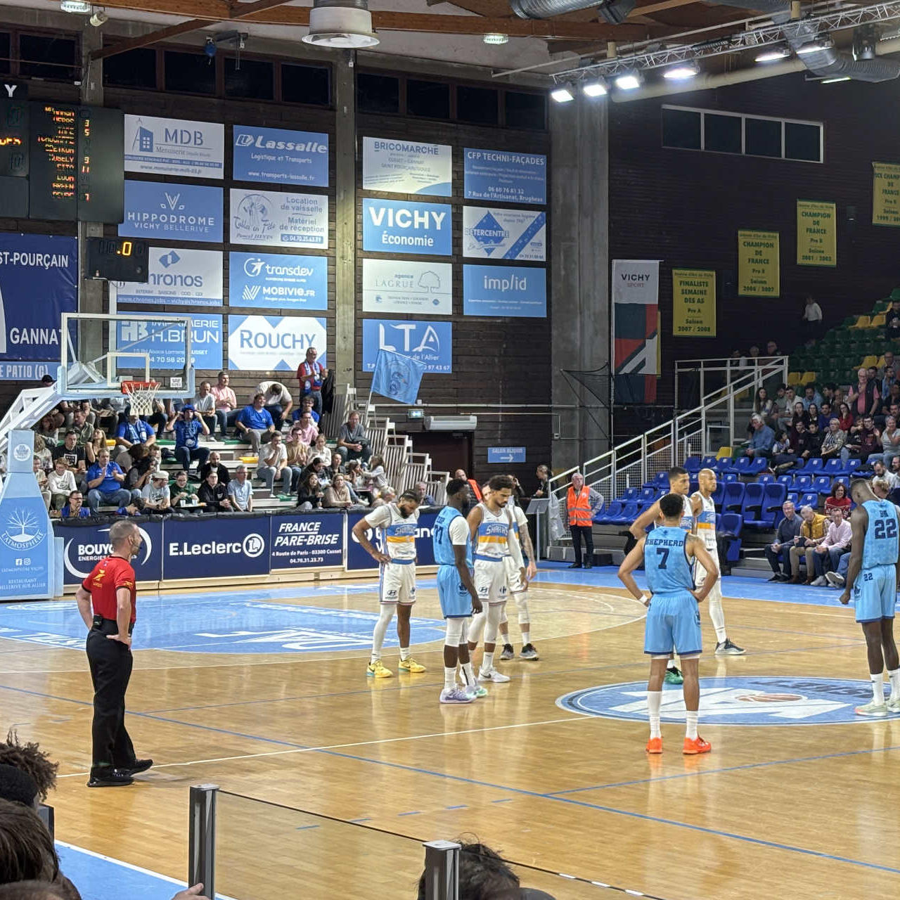 Des joueurs de basket et un arbitre sur le parquet au tout début d'un match.