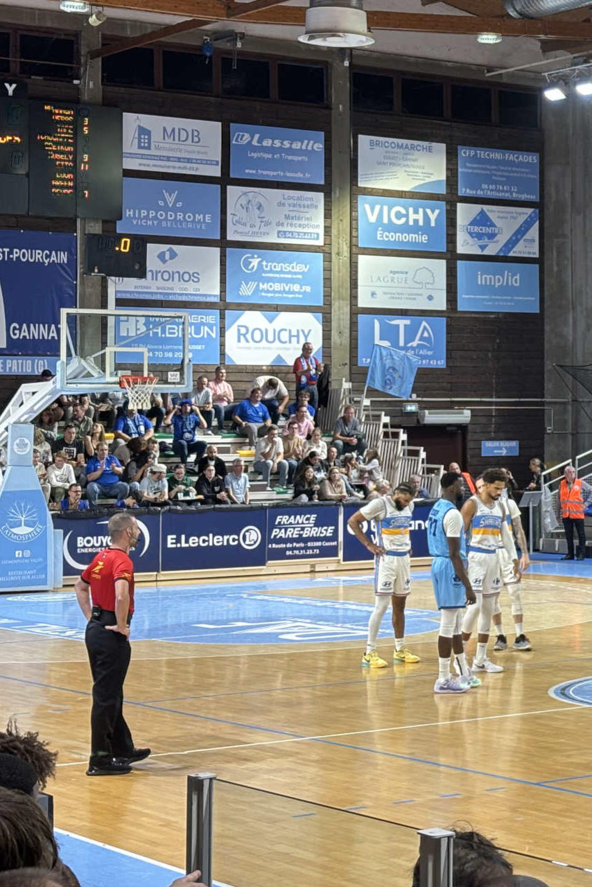 Des joueurs de basket et un arbitre sur le parquet au tout début d'un match.