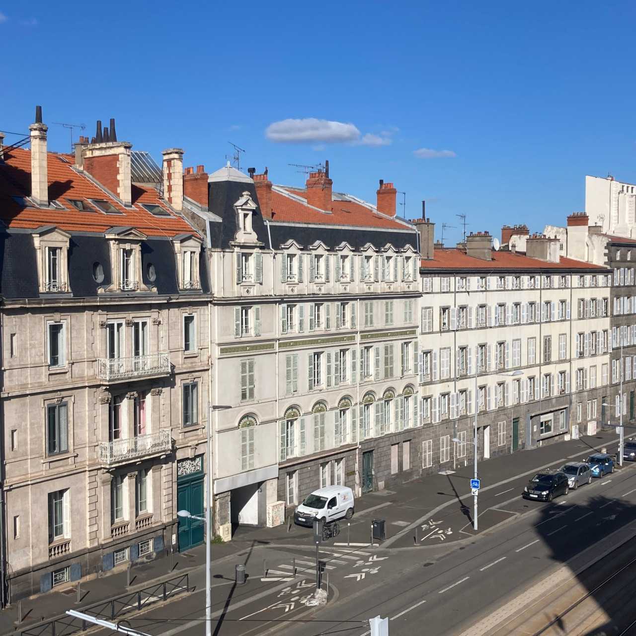 Vue de la rue Montlosier à Clermont-Ferrand avec les façades d'immeubles, la route et la voie de tramway en contrebas.