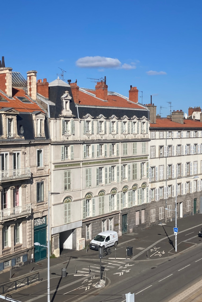 Vue de la rue Montlosier à Clermont-Ferrand avec les façades d'immeubles, la route et la voie de tramway en contrebas.