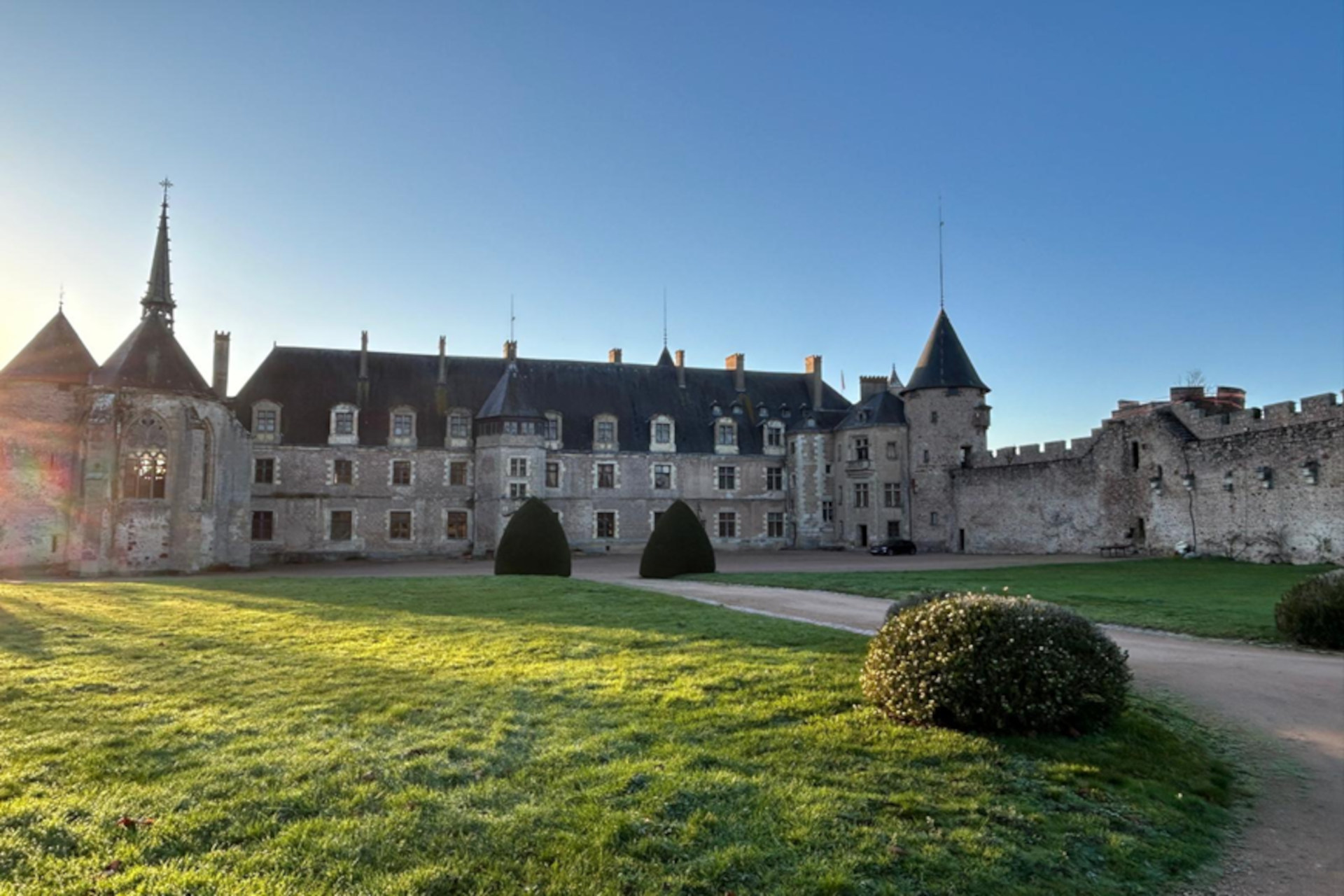 Le Château de Lapalisse avec une partie du jardin sous le soleil couchant.