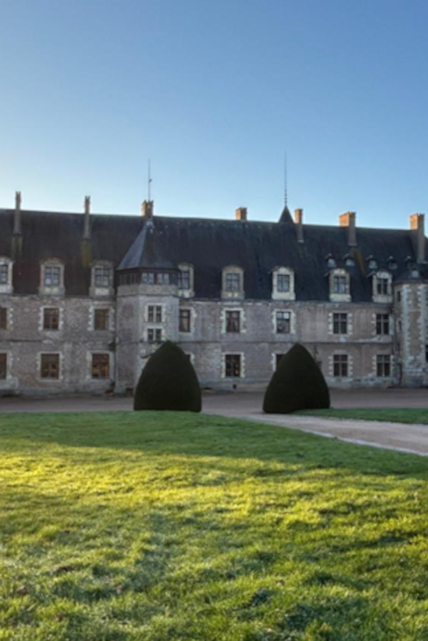 Le Château de Lapalisse avec une partie du jardin sous le soleil couchant.