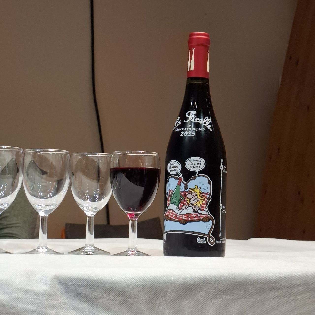 Des bouteilles, des verres et des dégustateurs de la Ficelle illustrée, du vin rouge de Saint-Pourçain-sur-Sioule.