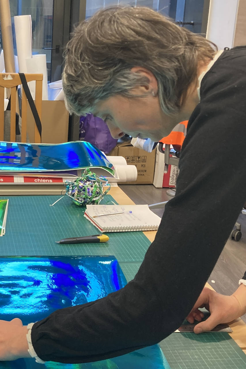 Femme en train de découper une feuille vinyle autocollante dans le fablab de Vichy.