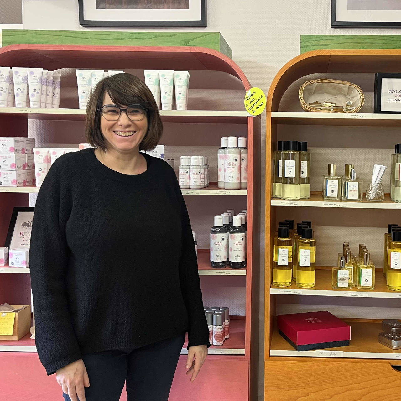Sonia se tient devant une sélection de produits vendus au sein de la boutique de l'abbaye.