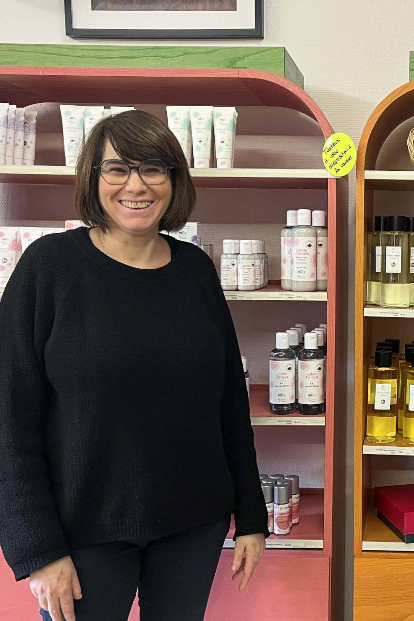 Sonia se tient devant une sélection de produits vendus au sein de la boutique de l'abbaye.