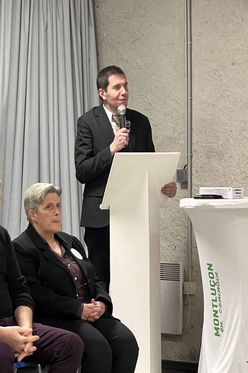 Debout, Pierre Mothet prend la parole derrière un pupitre en compagnie de plusieurs personnes (assises) de sa liste.