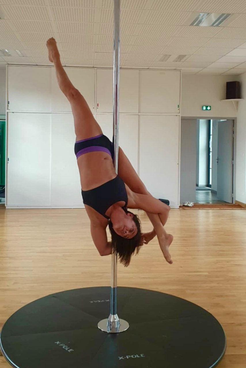 Nathalie Poncy se tient à une barre, lors d'un entraînement de pole dance.