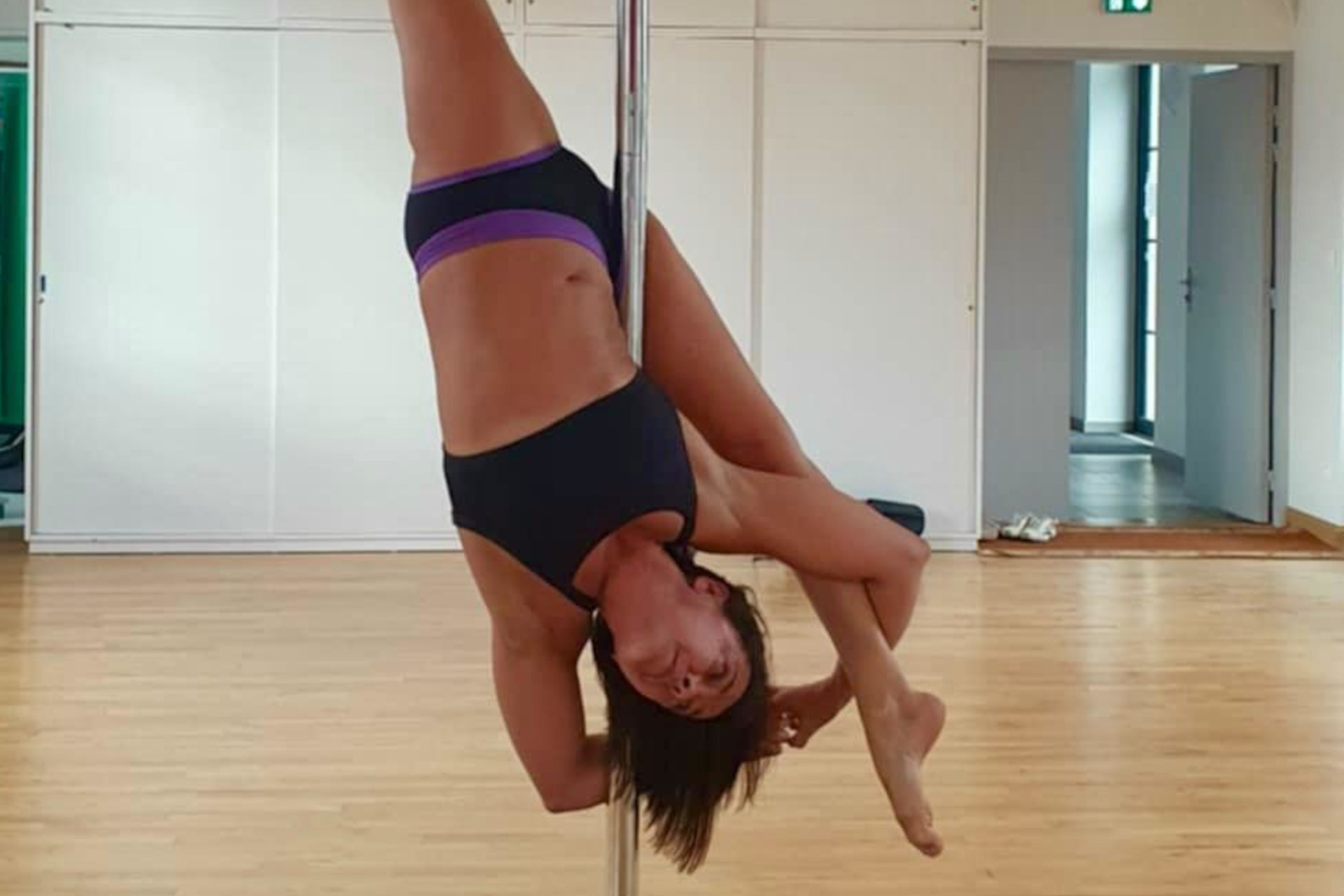 Nathalie Poncy se tient à une barre, lors d'un entraînement de pole dance.